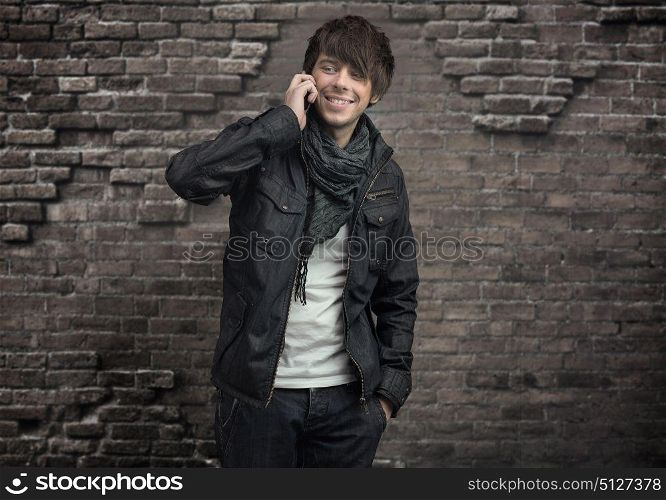 Handsome man holding a smartphone and posing on a brick background