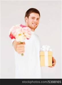 handsome man holding bouquet of flowers and gift box