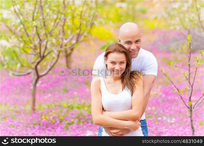 Handsome man hugging his attractive woman in spring park, beautiful nature, strong feelings, love and tenderness concept