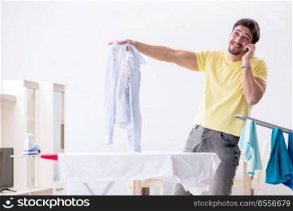 Handsome man husband doing clothing ironing at home