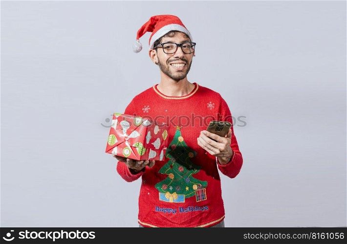 Handsome man in christmas hat holding gift and looking at phone, Guy in christmas hat holding gift box and smiling at smartphone, Christmas man holding gift box and telephone isolated