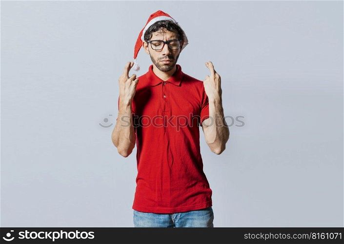 Handsome man in christmas hat making a wish on isolated background. Guy with christmas hat making a wish on isolated background, Hopeful man in christmas clothes making a wish