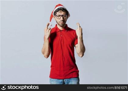Handsome man in christmas hat making a wish on isolated background. Guy with christmas hat making a wish on isolated background, Hopeful man in christmas clothes making a wish