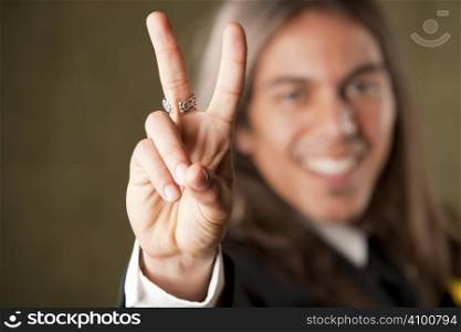 Handsome man in formal jacket with boutonniere making peace sign