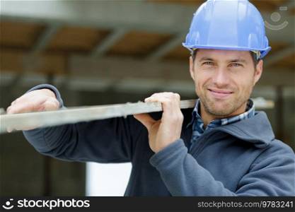 handsome man in helmet holds wooden beam