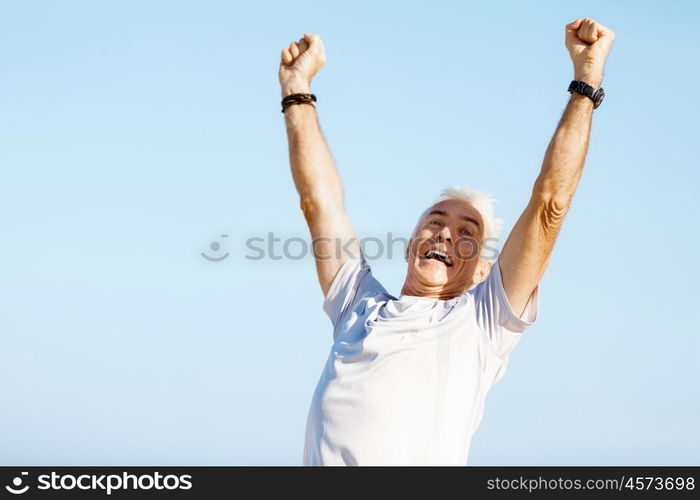 Handsome man in sport wear with outstretched arms. Handsome man in sport wear with outstretched arms standing on beach