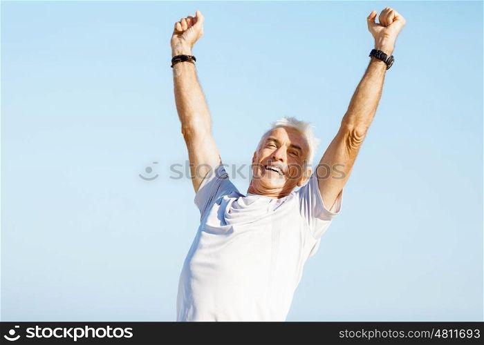 Handsome man in sport wear with outstretched arms. Handsome man in sport wear with outstretched arms standing on beach