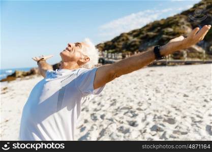 Handsome man in sport wear with outstretched arms. Handsome man in sport wear with outstretched arms standing on beach