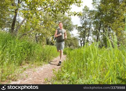 Handsome man in sportswear running in the forest