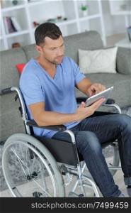 handsome man in wheelchair using a tablet at home