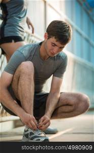 Handsome man lacing his shoes before running outdoors