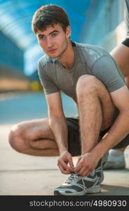 Handsome man lacing his shoes before running outdoors