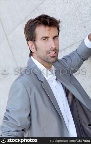 Handsome man leaning on grey wall