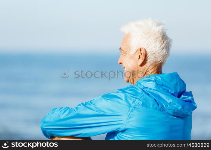 Handsome man looking thoughtful while standing alone on beach. Handsome man looking thoughtful while standing alone on beach in sports wear