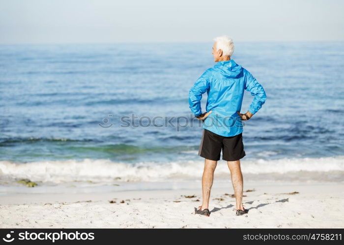 Handsome man looking thoughtful while standing alone on beach. Handsome man looking thoughtful while standing alone on beach in sports wear