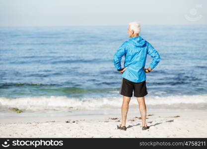 Handsome man looking thoughtful while standing alone on beach. Handsome man looking thoughtful while standing alone on beach in sports wear