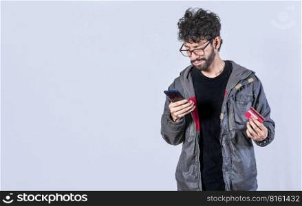 Handsome man paying from his phone with a credit card, Man paying online with a credit card from his cell phone. Happy man paying online with his cell phone and debit card.