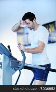 Handsome man running on the treadmill in modern gym