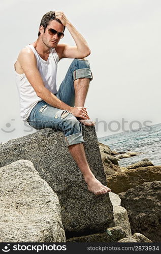 Handsome man sitting on a rock