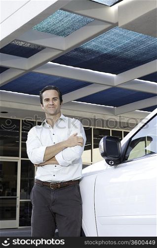 Handsome man standing besides car with arms crossed
