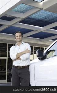 Handsome man standing besides car with arms crossed