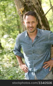 Handsome man standing by a tree