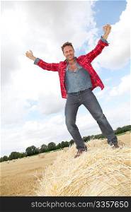 Handsome man standing on a hay bale