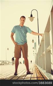 Handsome man tourist on pier. Guy enjoying summer travel vacation by sea. Fashion full length. Instagram filtered.. Handsome man tourist on pier. Fashion summer.