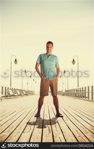 Handsome man tourist on pier. Guy enjoying summer travel vacation by sea. Fashion full length. Instagram filtered.. Handsome man tourist on pier. Fashion summer.