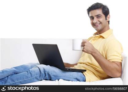 Handsome man using laptop while having coffee
