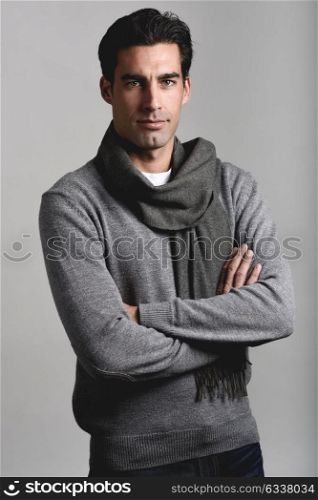 Handsome man wearing winter clothes smiling on white background. Young male with swater and scarf looking at camera. Studio shot