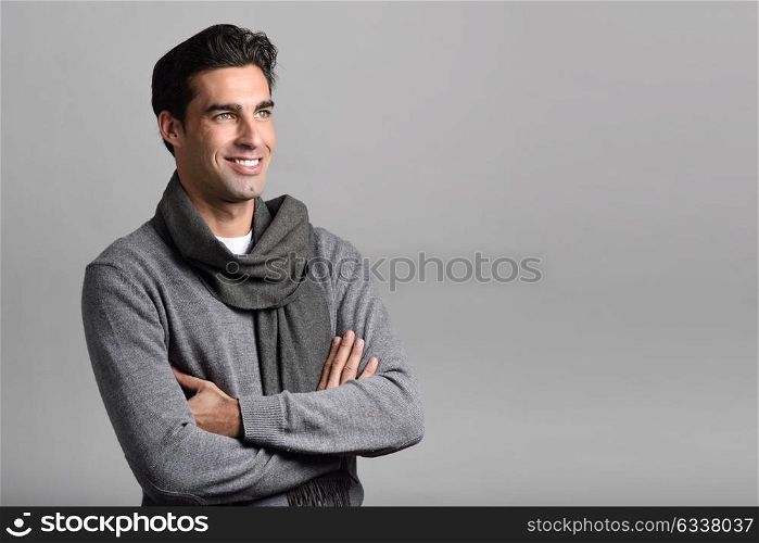 Handsome man wearing winter clothes smiling on white background. Young male with swater and scarf. Studio shot