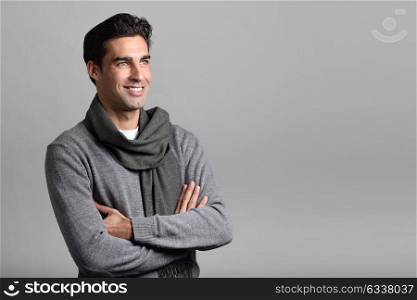 Handsome man wearing winter clothes smiling on white background. Young male with swater and scarf. Studio shot