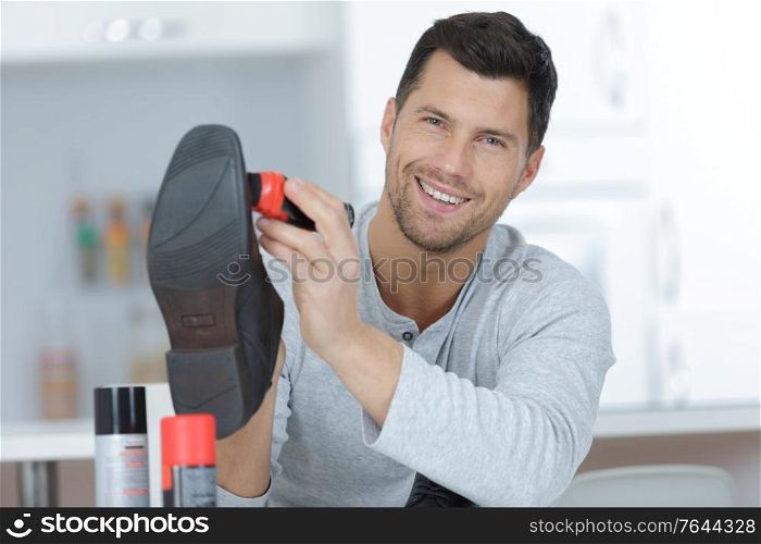 handsome man with brush cleaning black leather shoe