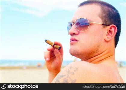 handsome man with cigar on beach is looking sideways