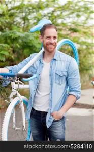 Handsome man with denim clothes enjoying with his bike in the park