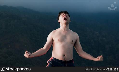 handsome man with no shirt standing on the top of mountain with white fog. Successful man hiker open arms enjoying beautiful sunrise in morning mountains.