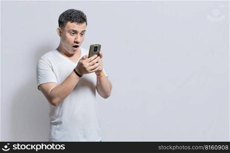 Handsome man with surprised expression with his phone in his hand, An astonished person with his cell phone on isolated background