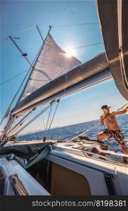 Handsome Man Working on Sailboat. Beautiful Sunny Day. Sailor Enjoying Travel and Sport. Summer Holidays.. Enjoying Sailing in the Sea
