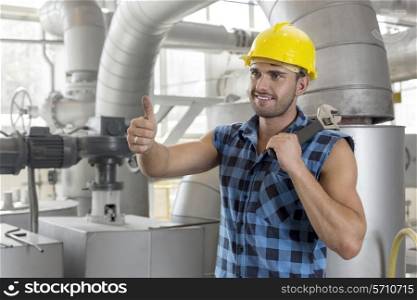 Handsome manual worker gesturing thumbs up in industry
