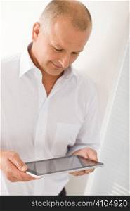 Handsome mature businessman holding look down touch tablet screen computer