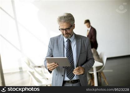 Handsome mature businessman using his digital tablet in the office
