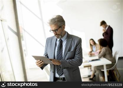 Handsome mature businessman using his digital tablet in the office