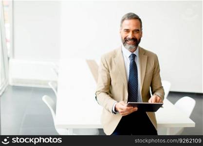 Handsome mature businessman with digital tablet in the office