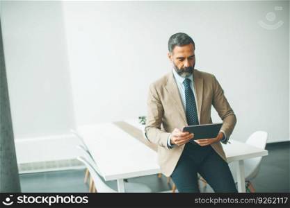 Handsome mature businessman with digital tablet in the office