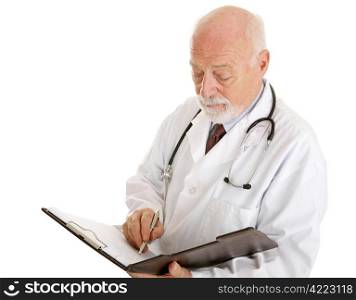 Handsome mature doctor making notations in a patients chart. Isolated on white.