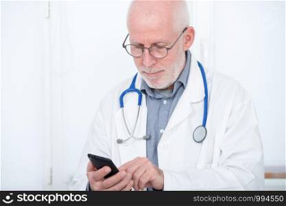 handsome mature doctor on phone in his office