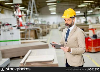 Handsome mature engineer in the factory with digital tablet