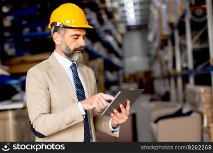 Handsome mature engineer in the warehouse with digital tablet