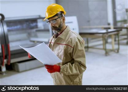 Handsome mature engineer looking at a plan in the factory